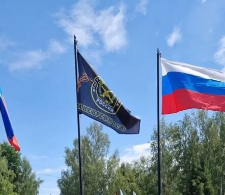 Флаг России и флаг подразделения на флагштоках у воинского захоронения